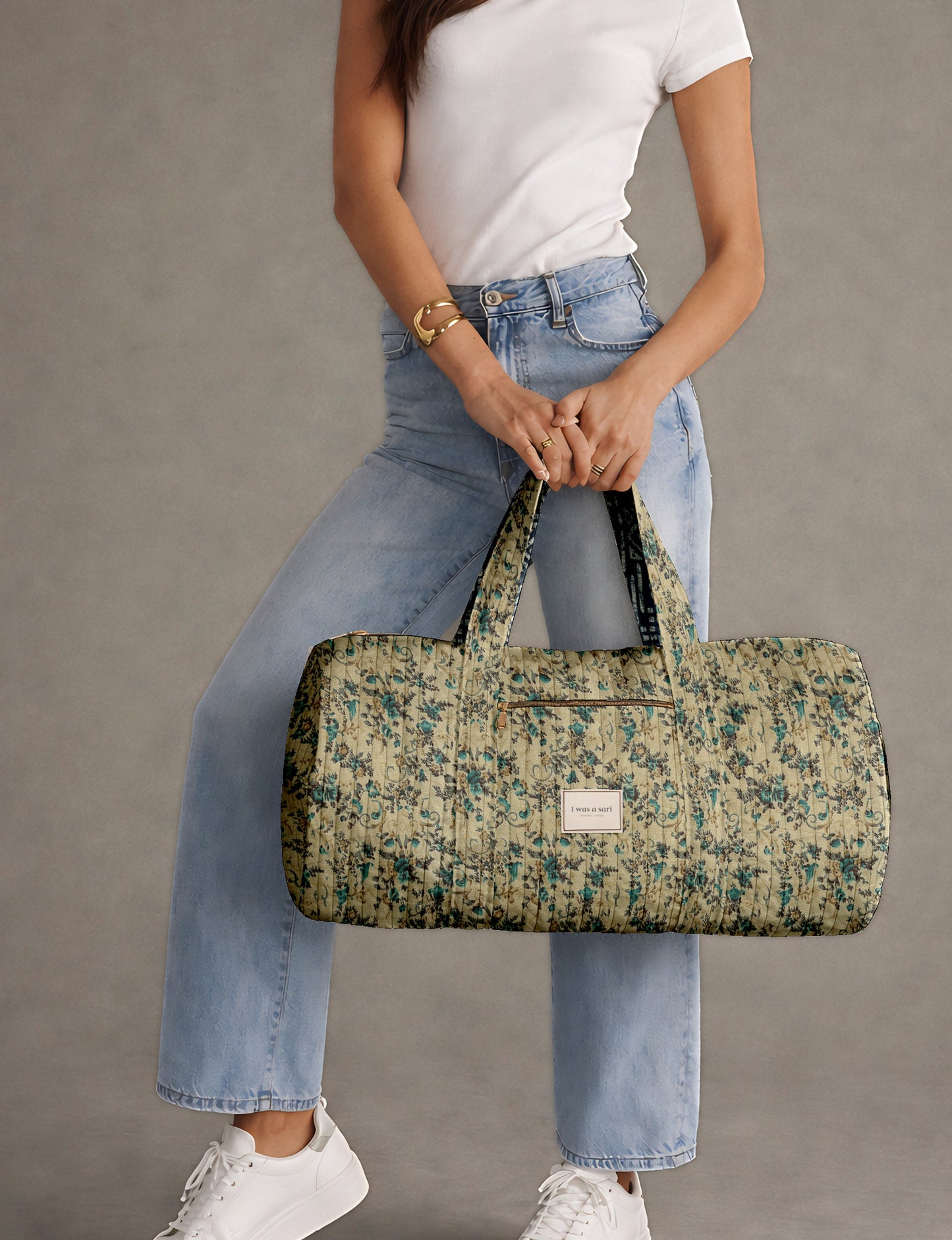 Brown paisley quilted bowling bag with front zipper pocket, held by person wearing white shirt and light blue jeans