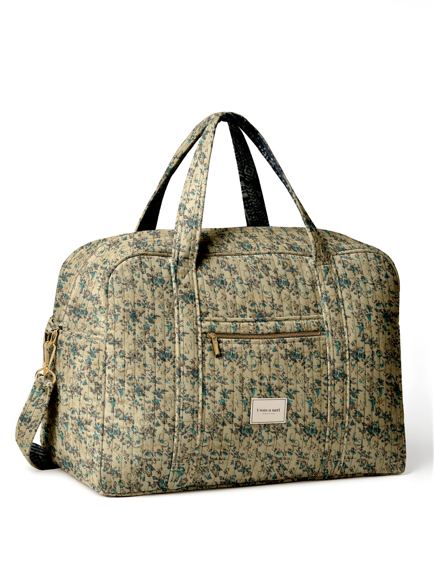 Brown quilted duffle bag with paisley pattern, front zip pocket, dual handles, and label reading "I was a sari"