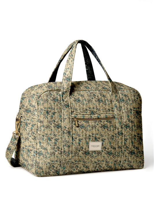 Brown quilted duffle bag with paisley pattern, front zip pocket, dual handles, and label reading "I was a sari"