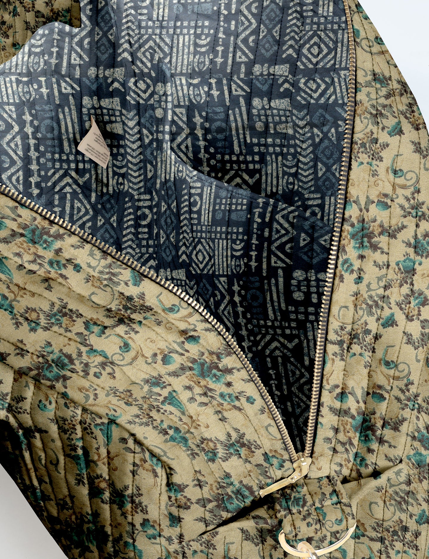 Brown quilted duffle bag with paisley pattern, front zip pocket, dual handles, and label reading "I was a sari"