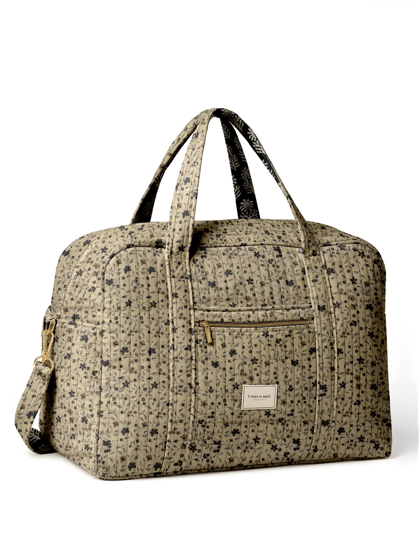 Brown quilted duffle bag with paisley pattern, front zip pocket, dual handles, and label reading "I was a sari"