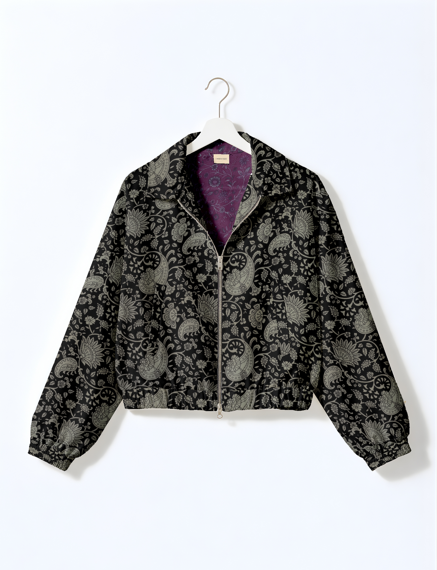 Women's cropped bomber jacket with twin metallic front zippers, welt pockets, elasticated hem and cuffs, and contrast sari print lining.