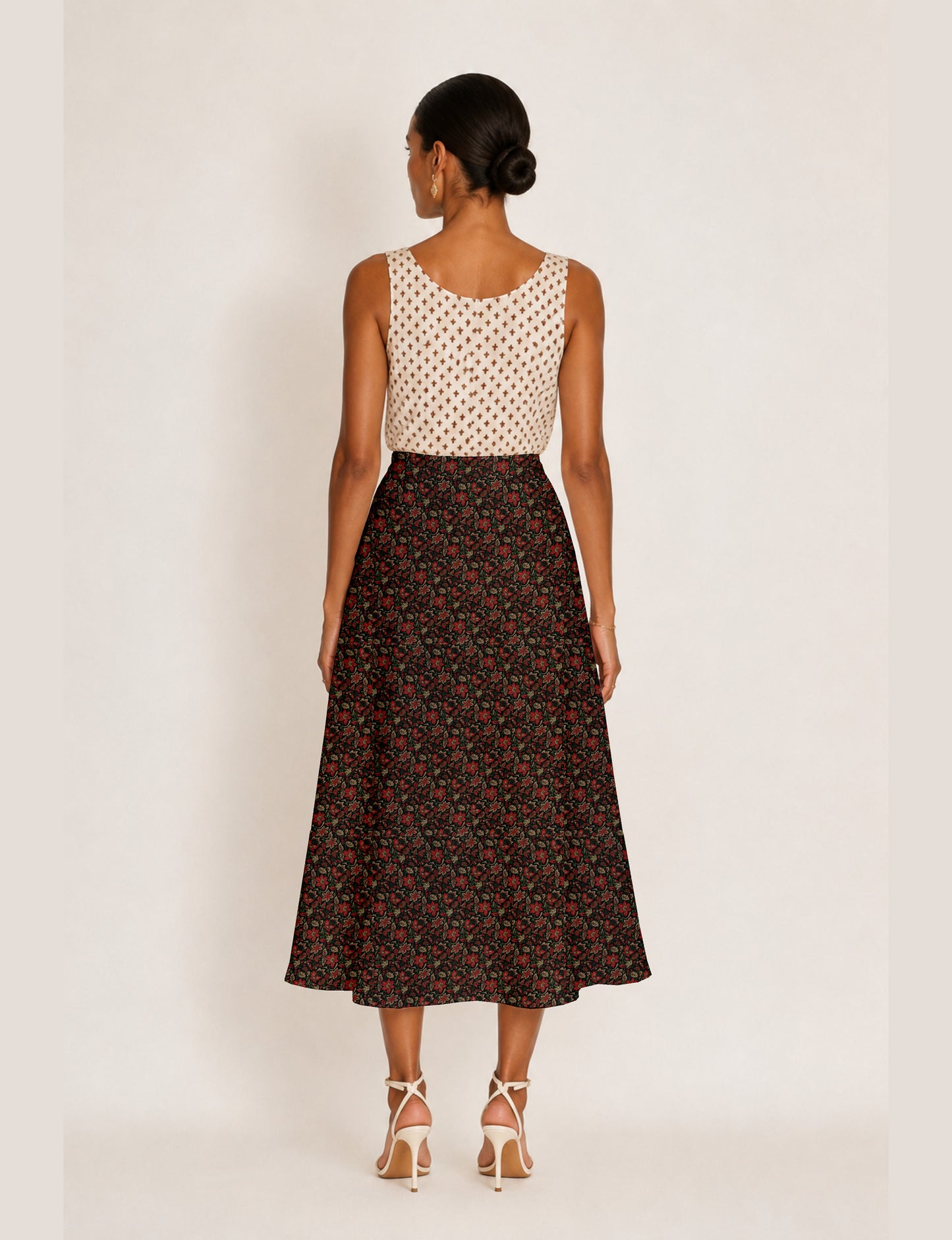 Woman wearing a yellow and black micro patterned A-line skirt with front slit, paired with beige sleeveless top and black