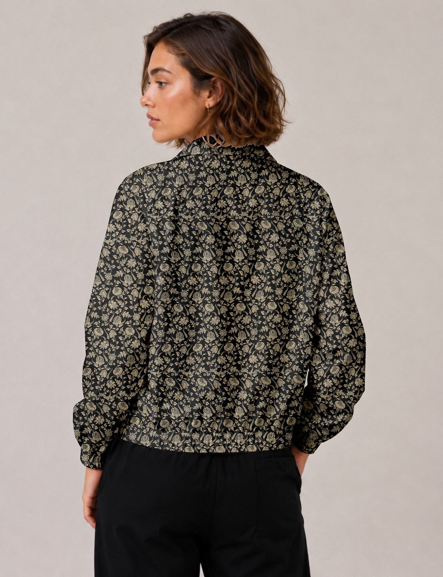 Brown floral bomber jacket with front zipper, elastic cuffs and hem, hanging on white hanger, red floral inner lining visible