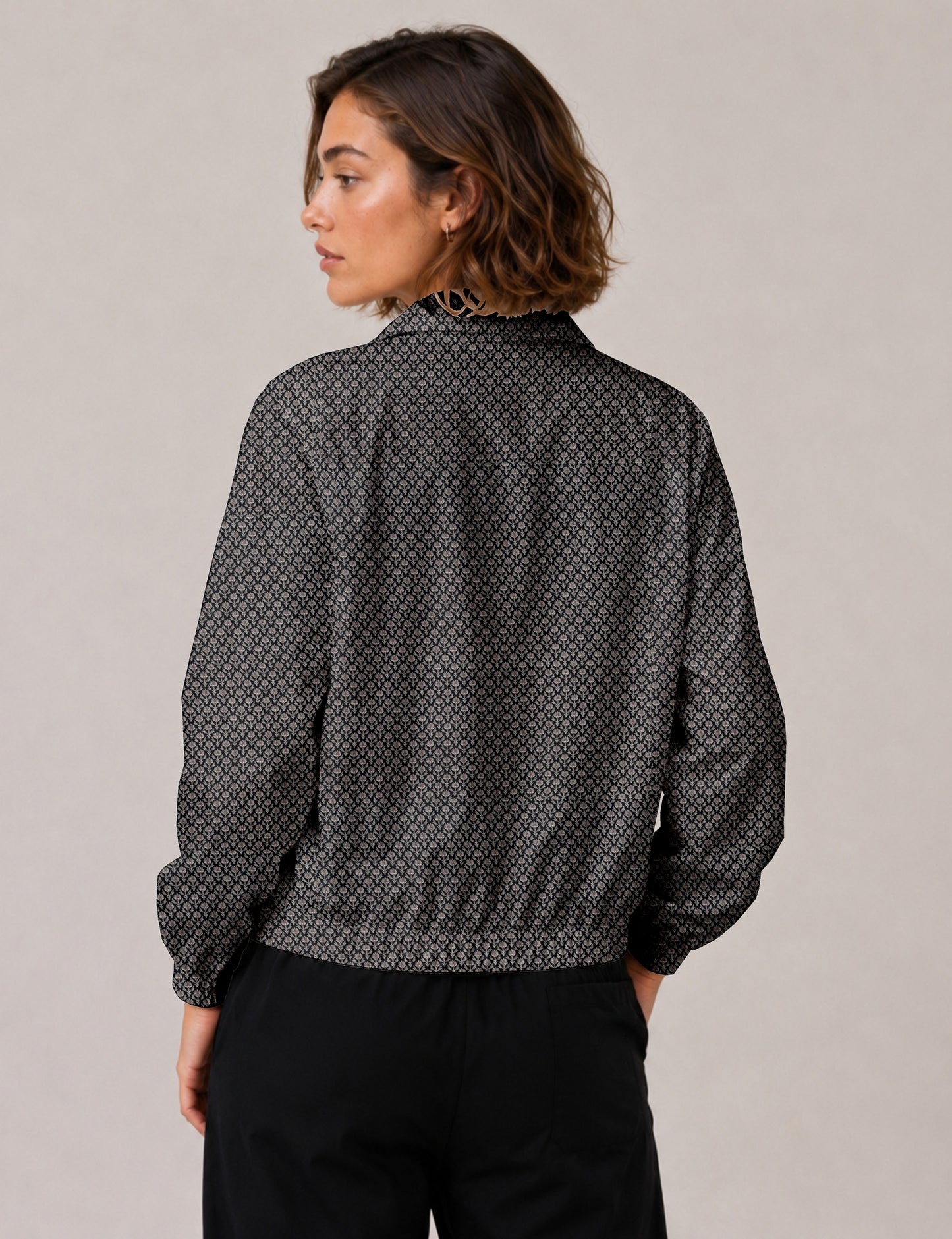 Brown floral bomber jacket with front zipper, elastic cuffs and hem, hanging on white hanger, red floral inner lining visible