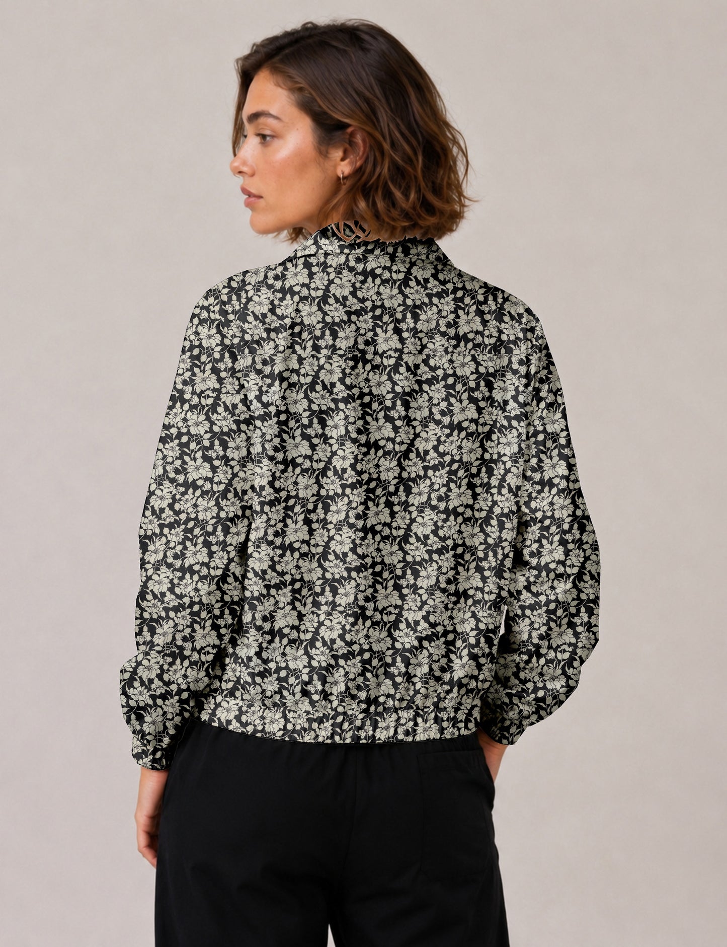 Woman wearing a yellow floral bomber jacket with front zipper, elastic cuffs, and side pockets, shown from front view