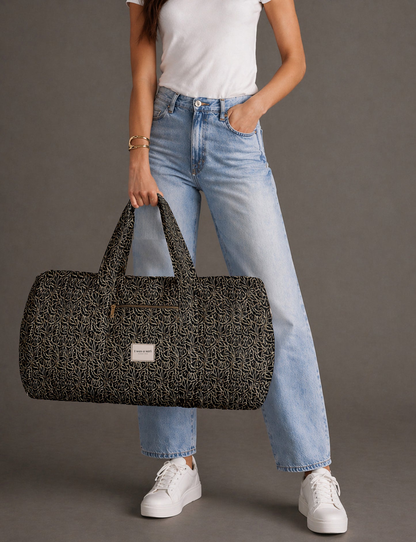 Quilted brown paisley barrel bag with double handles, front pocket, and gold zipper, shown in side angle view