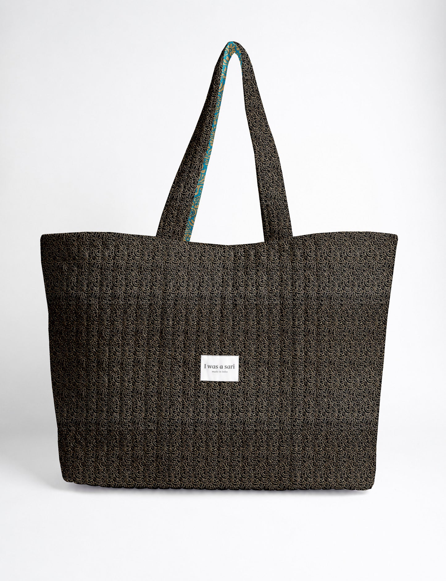Quilted yellow tropical patterned beach bag with long handles and white label reading "I was a sari" front view