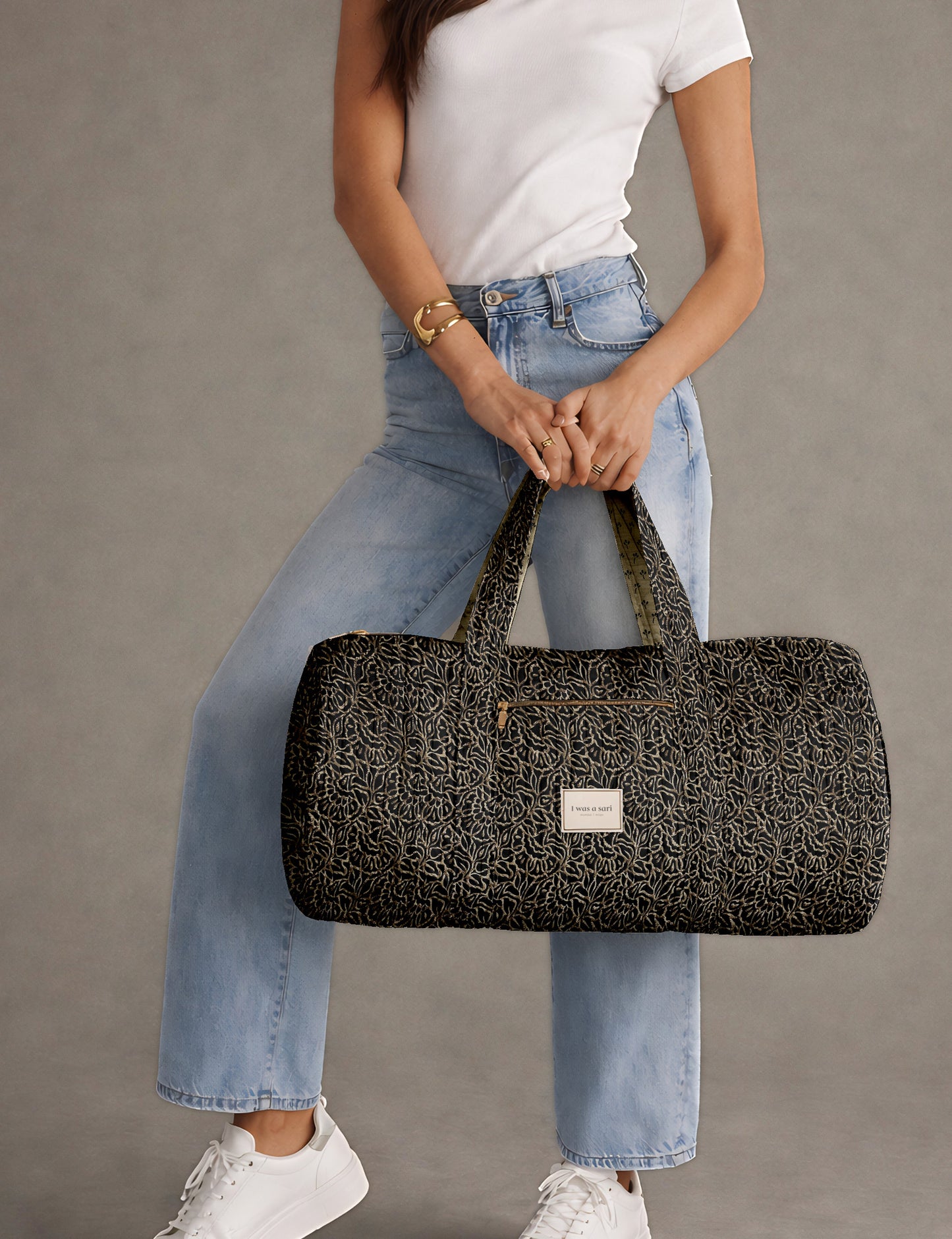 Brown paisley quilted bowling bag with front zipper pocket, held by person wearing white shirt and light blue jeans
