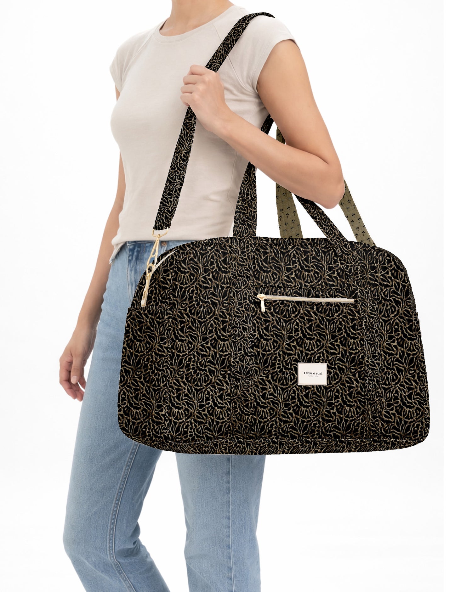 Brown quilted duffle bag with paisley pattern, front zip pocket, dual handles, and label reading "I was a sari"