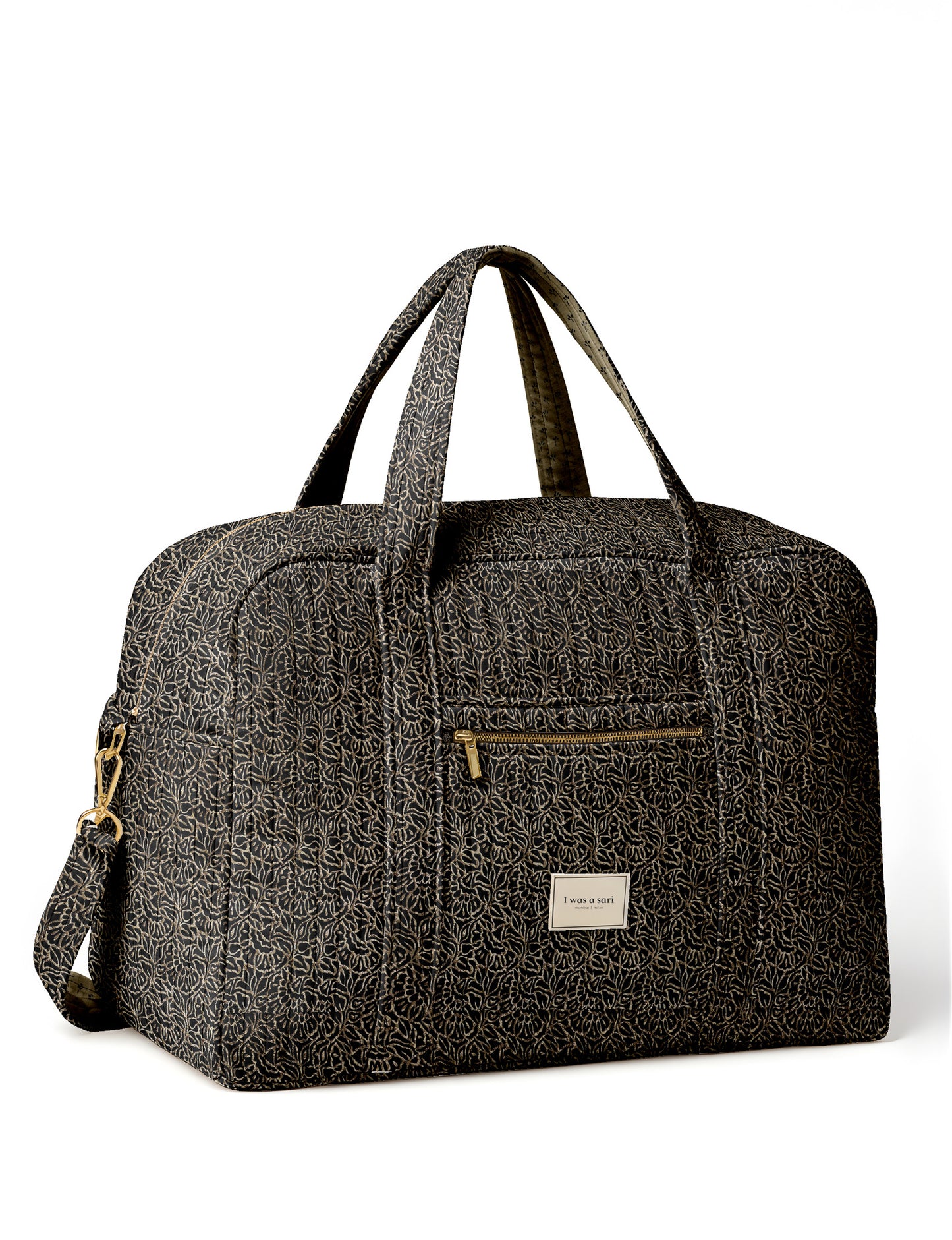 Brown quilted duffle bag with paisley pattern, front zip pocket, dual handles, and label reading "I was a sari"