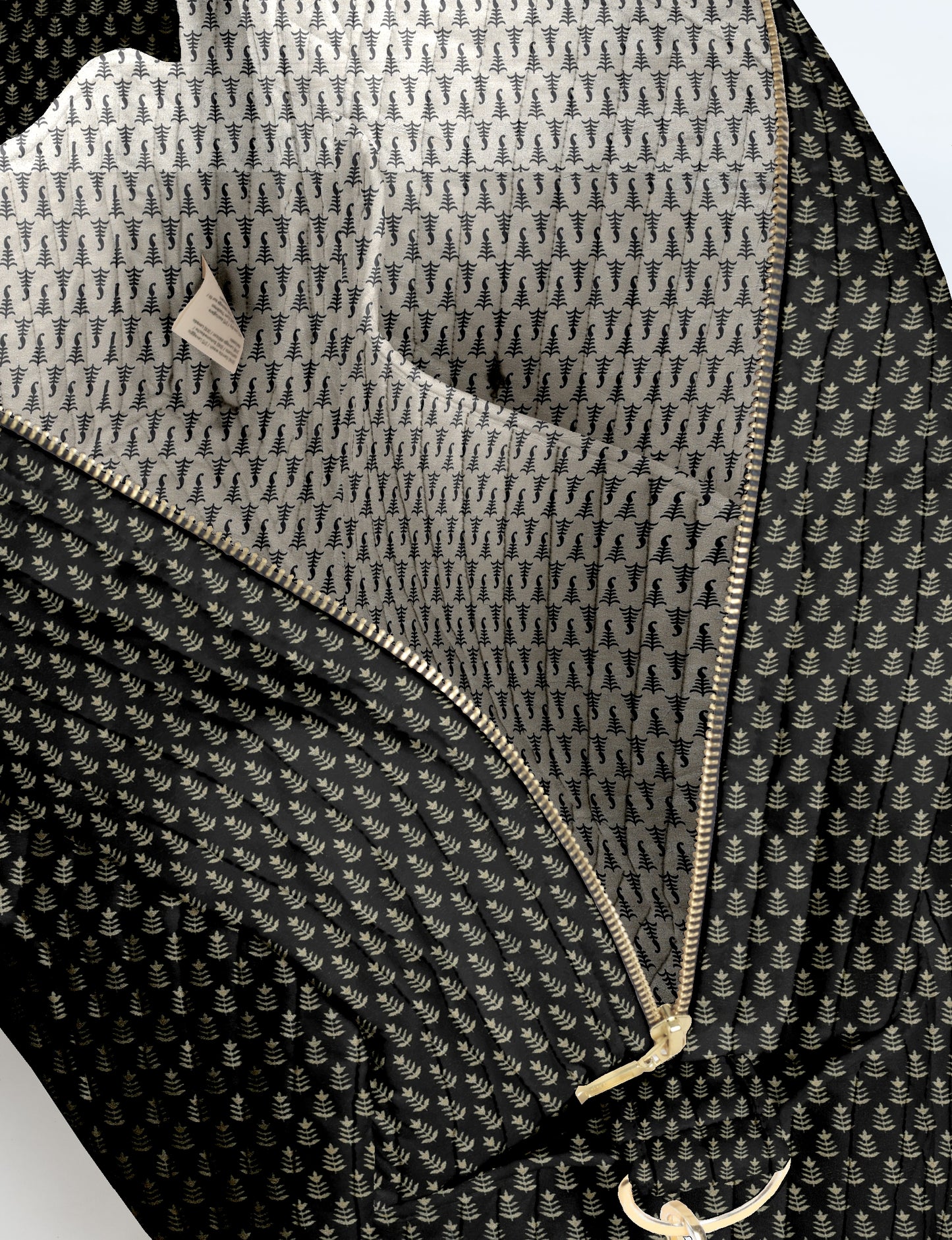 Black quilted duffle bag with beige micro leaf pattern, gold zipper, and interior pocket, shown open flat