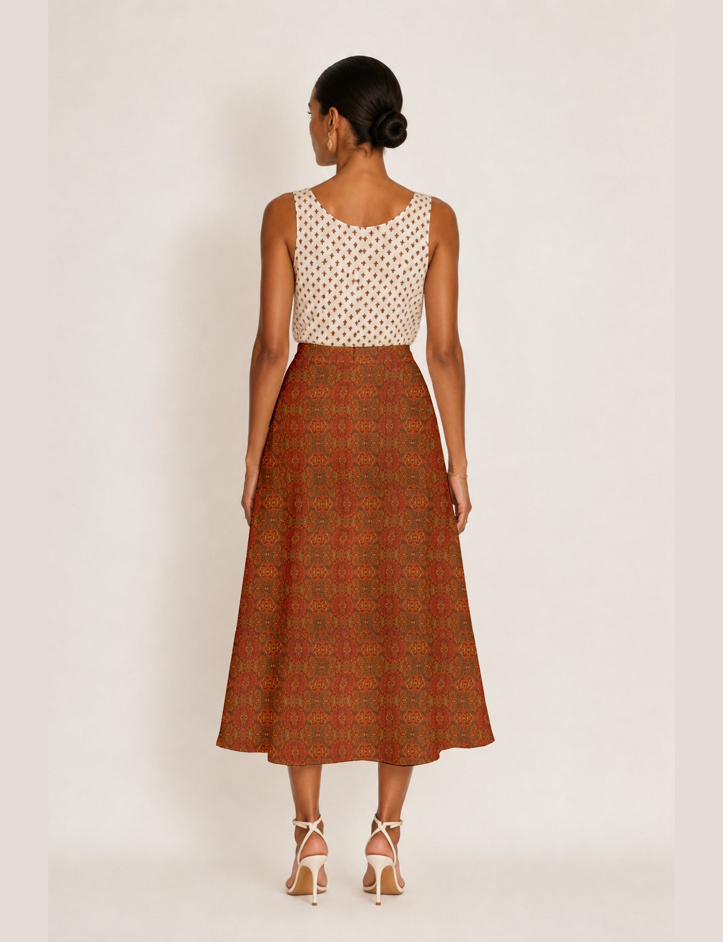 Woman wearing a yellow micro design A-line skirt with side slit, paired with a sleeveless beige top with small cross