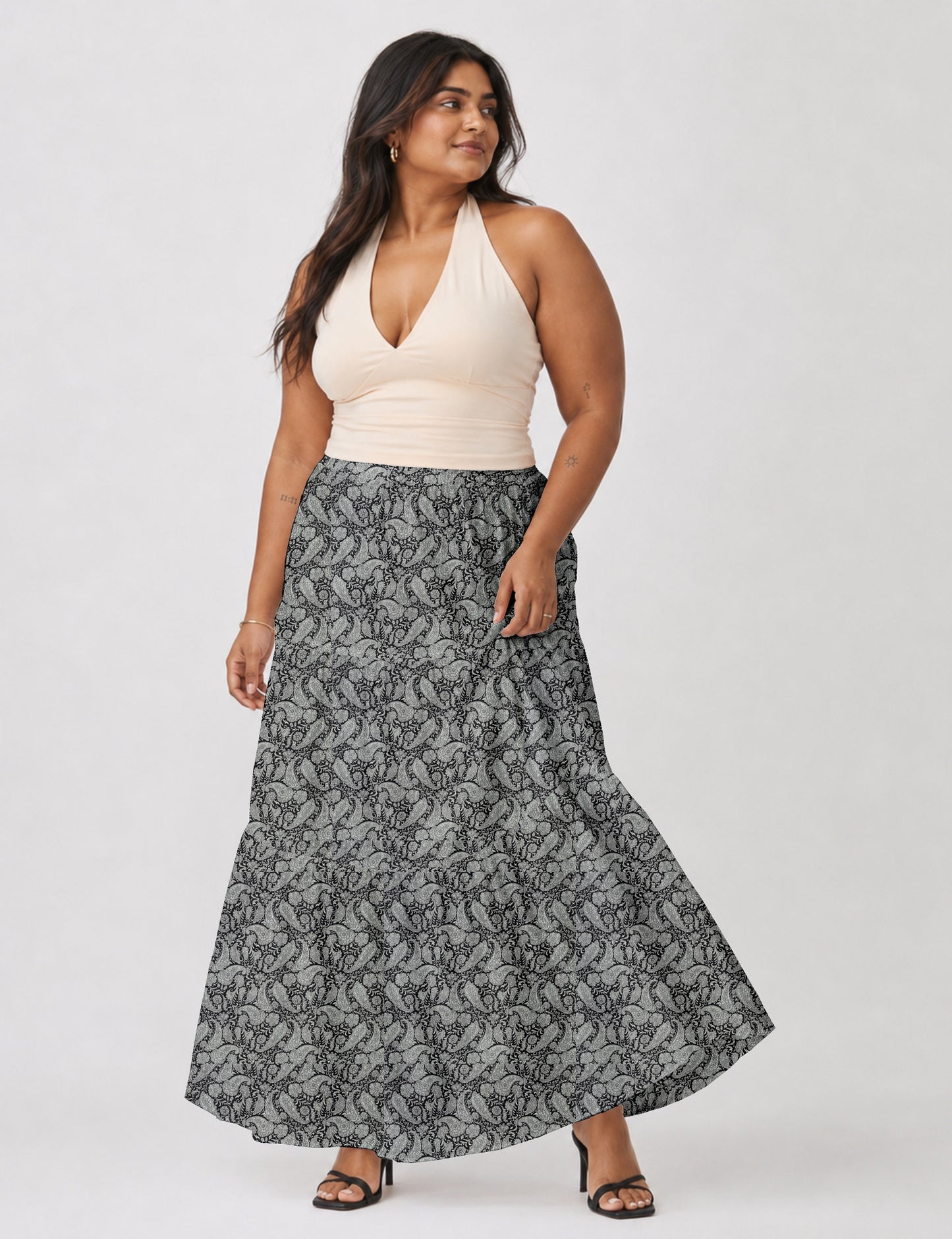 Woman wearing a yellow midi tiered skirt with a small geometric pattern, paired with a beige strapless top and white heels