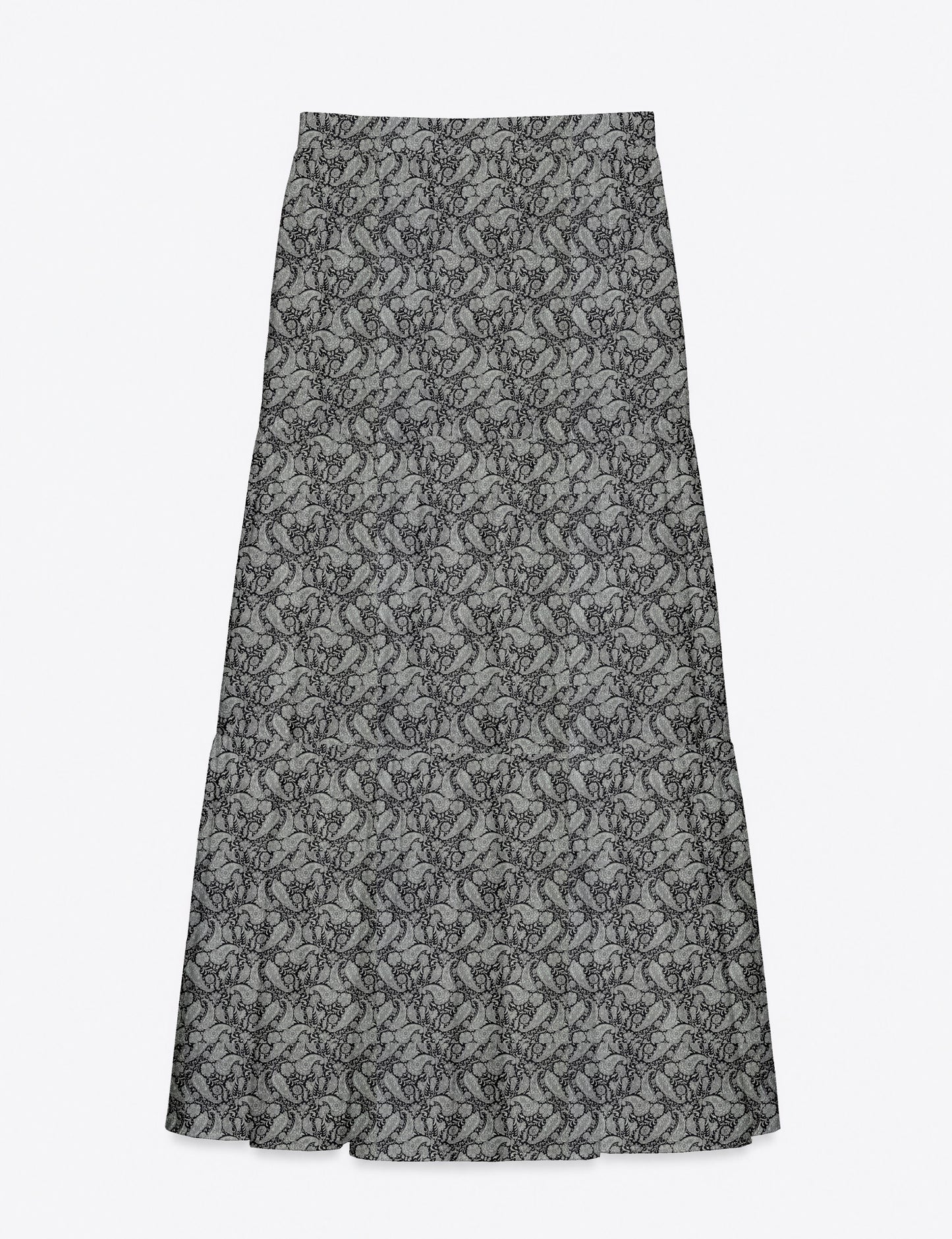 Woman wearing a yellow midi tiered skirt with a small geometric pattern, shown from the back, paired with beige top and