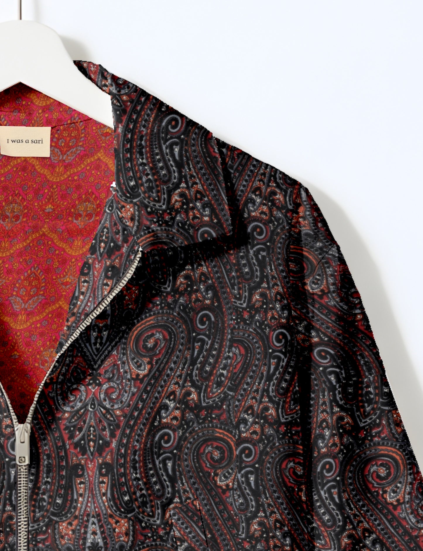Women's cropped bomber jacket with twin metallic front zippers, welt pockets, elasticated hem and cuffs, and contrast sari print lining.