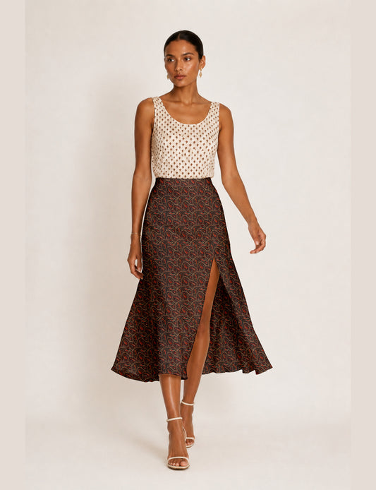 Woman wearing a yellow and black micro patterned A-line skirt with front slit, paired with beige sleeveless top and black