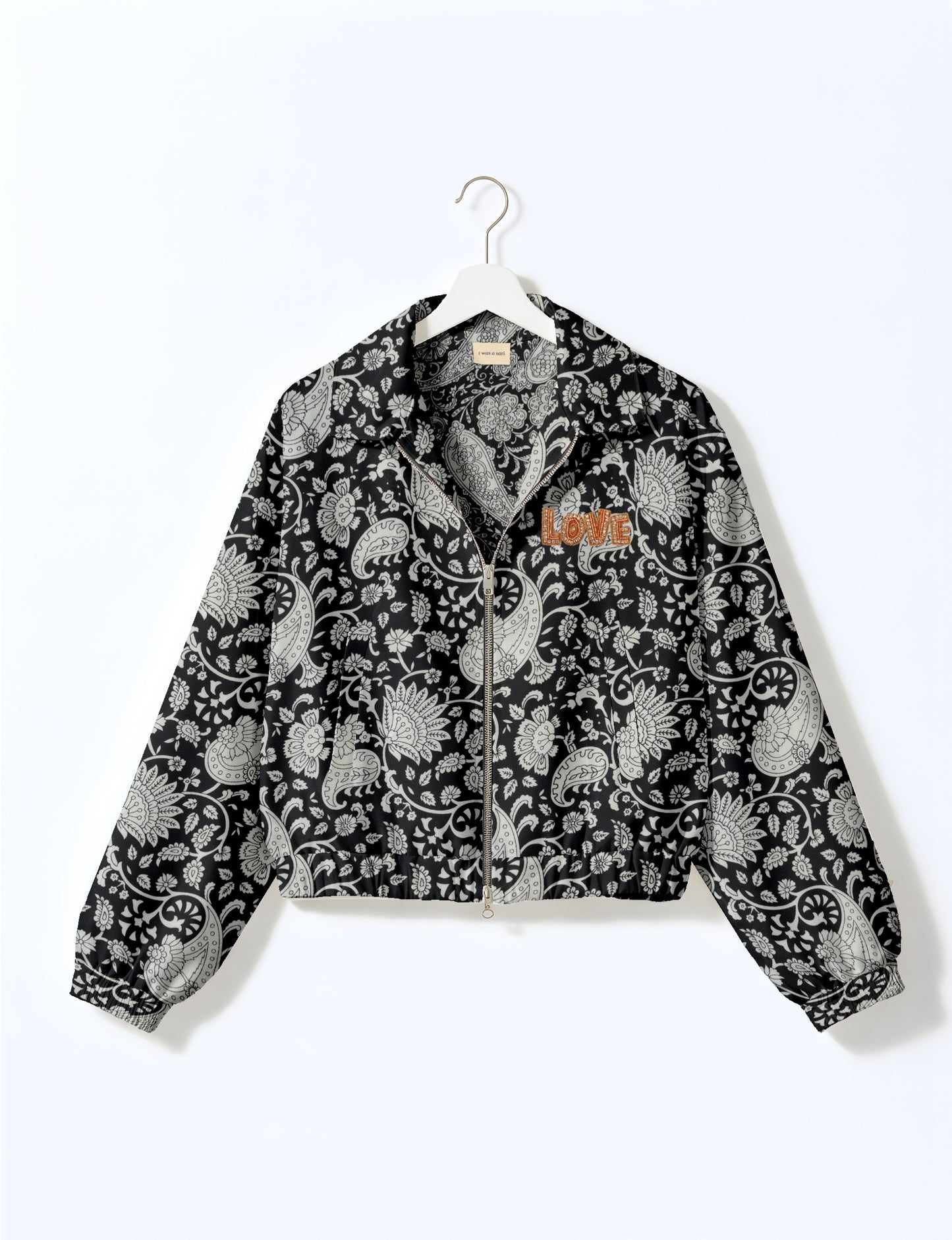 Black bomber jacket with white paisley floral pattern, front zipper, elastic cuffs and hem, and orange "LOVE" embroidery on