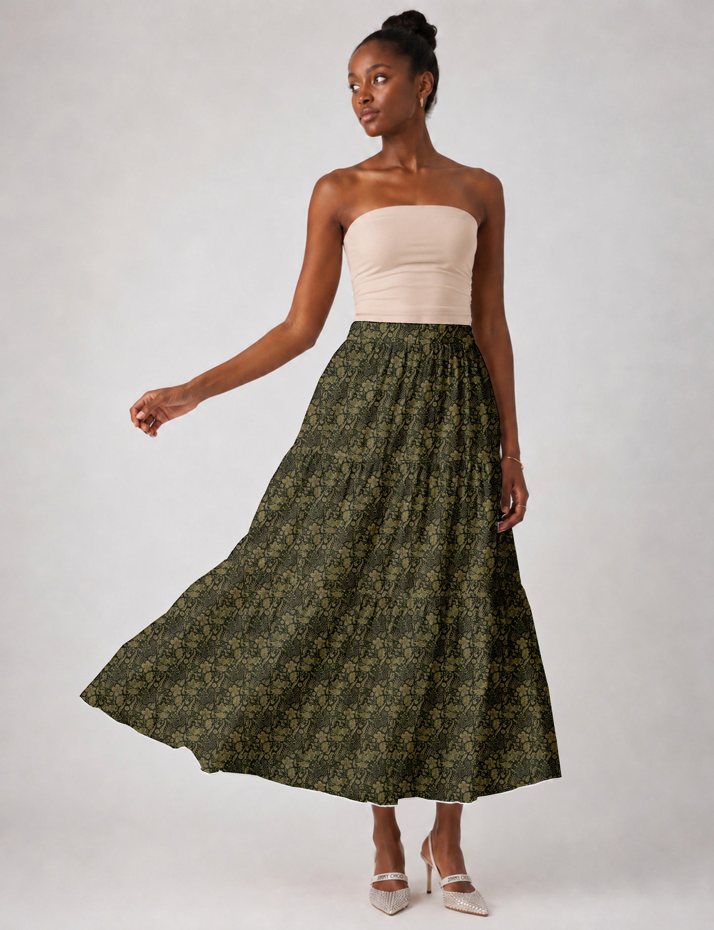Woman wearing a yellow midi tiered skirt with a small geometric pattern, paired with a beige strapless top and white heels
