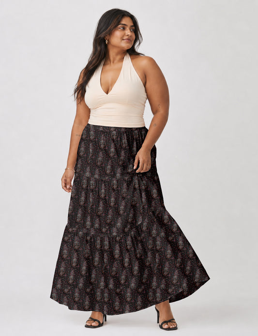 Woman wearing a yellow midi tiered skirt with a small geometric pattern, paired with a beige strapless top and white heels