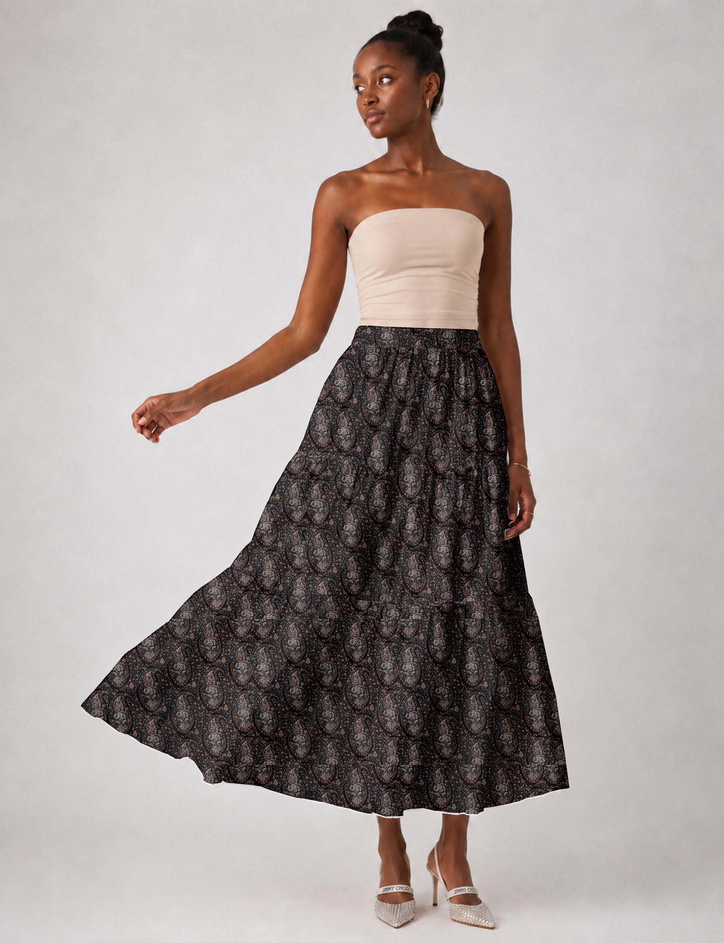 Woman wearing a yellow midi tiered skirt with a small geometric pattern, shown from the back, paired with beige top and