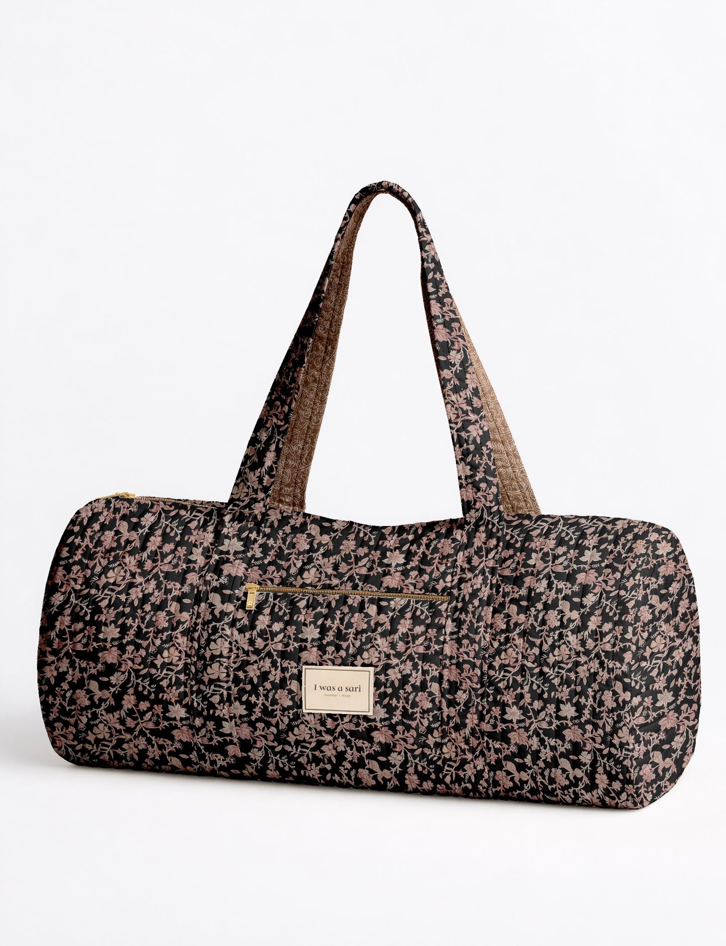 Brown paisley quilted bowling bag with front zipper pocket, held by person wearing white shirt and light blue jeans