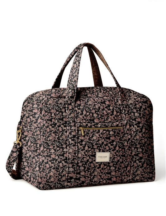 Brown quilted duffle bag with paisley pattern, front zip pocket, dual handles, and label reading "I was a sari"