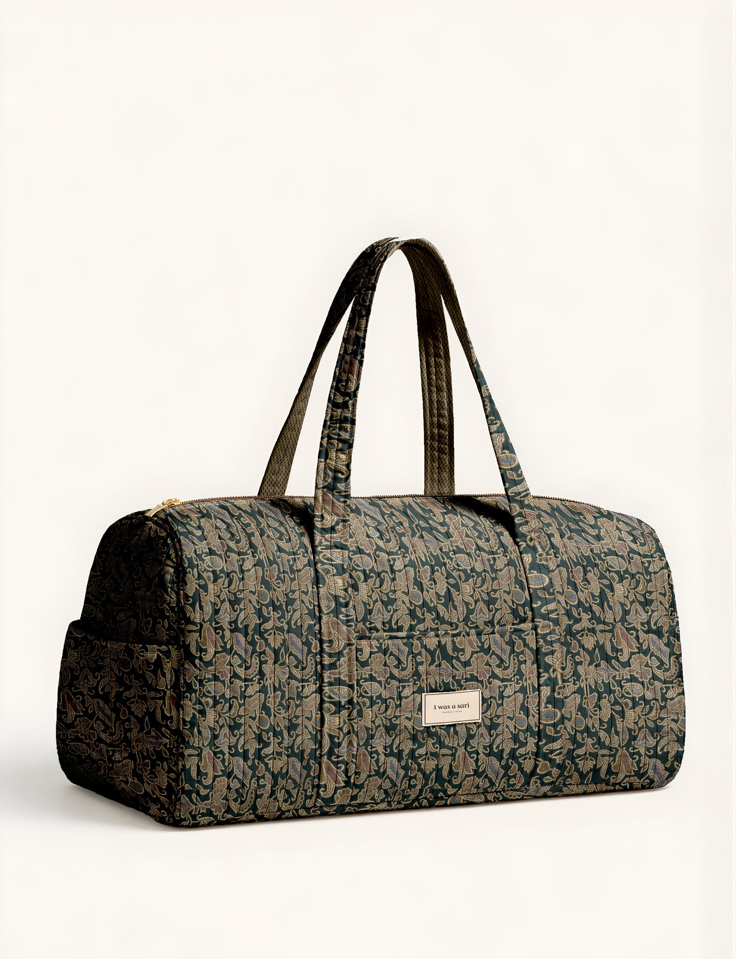 Quilted brown paisley barrel bag with double handles, front pocket, and gold zipper, shown in side angle view