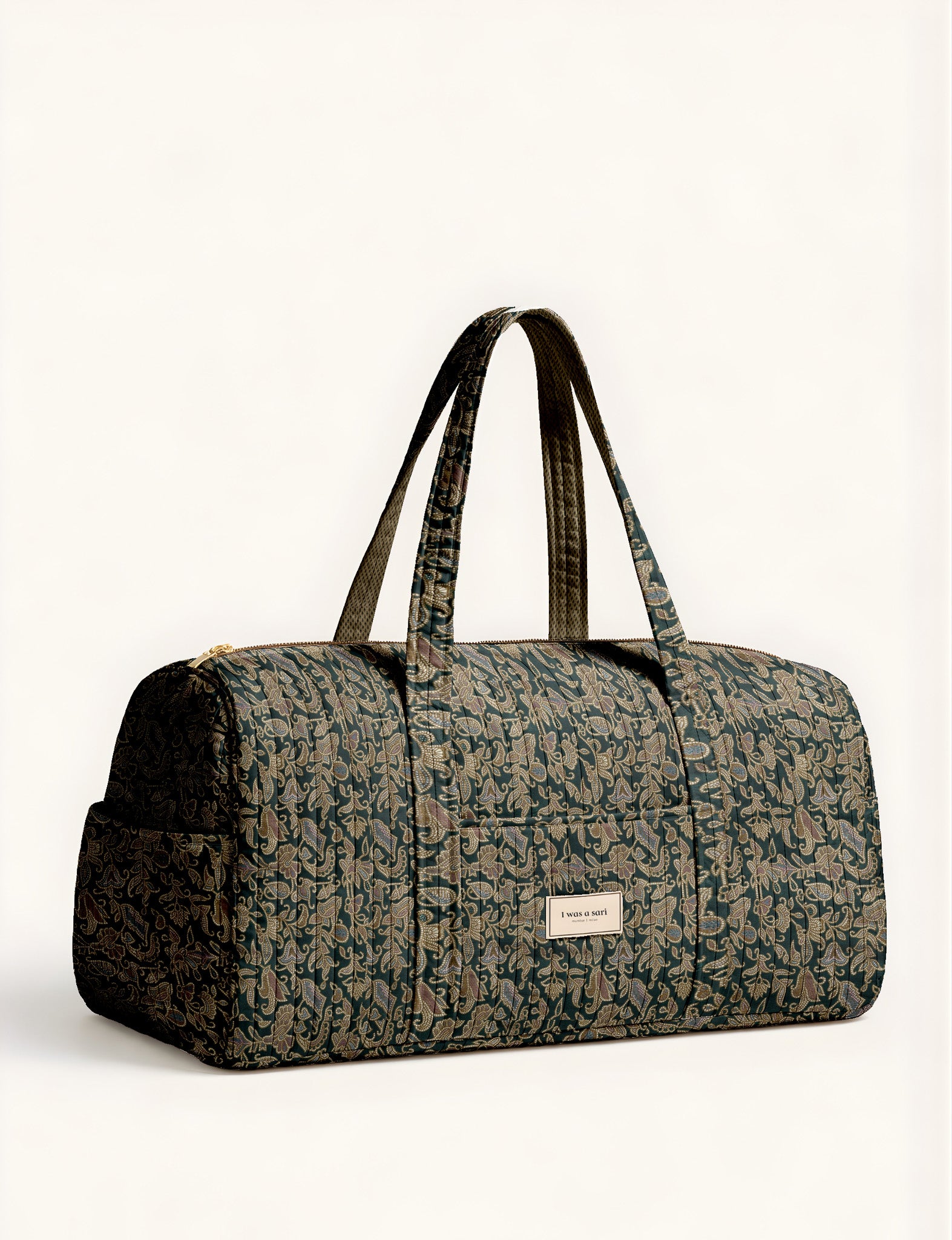 Quilted brown paisley barrel bag with double handles, front pocket, and gold zipper, shown in side angle view