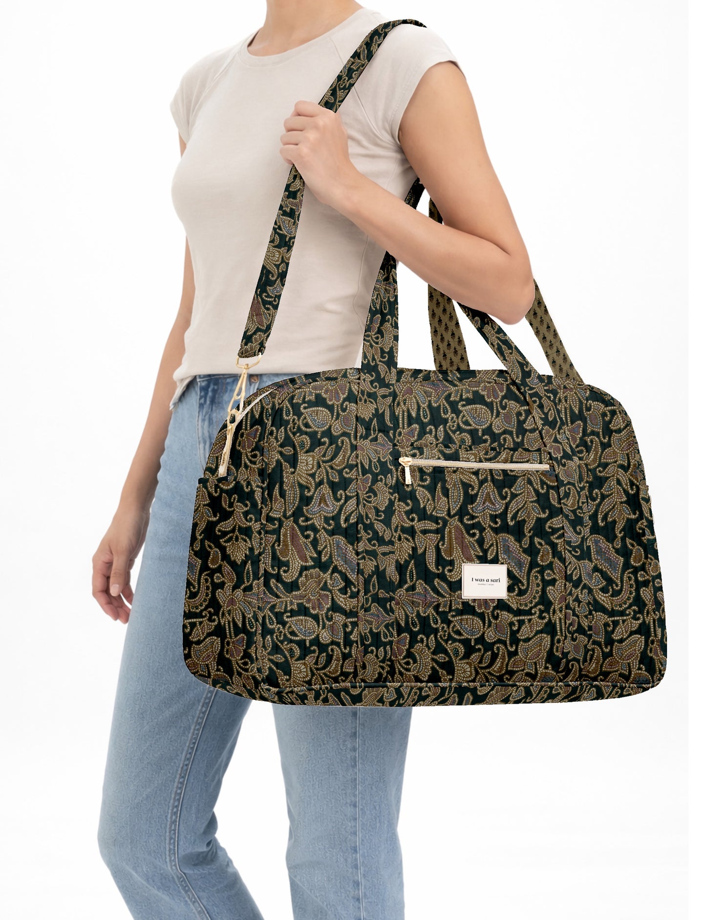 Brown quilted duffle bag with paisley pattern, front zip pocket, dual handles, and label reading "I was a sari"