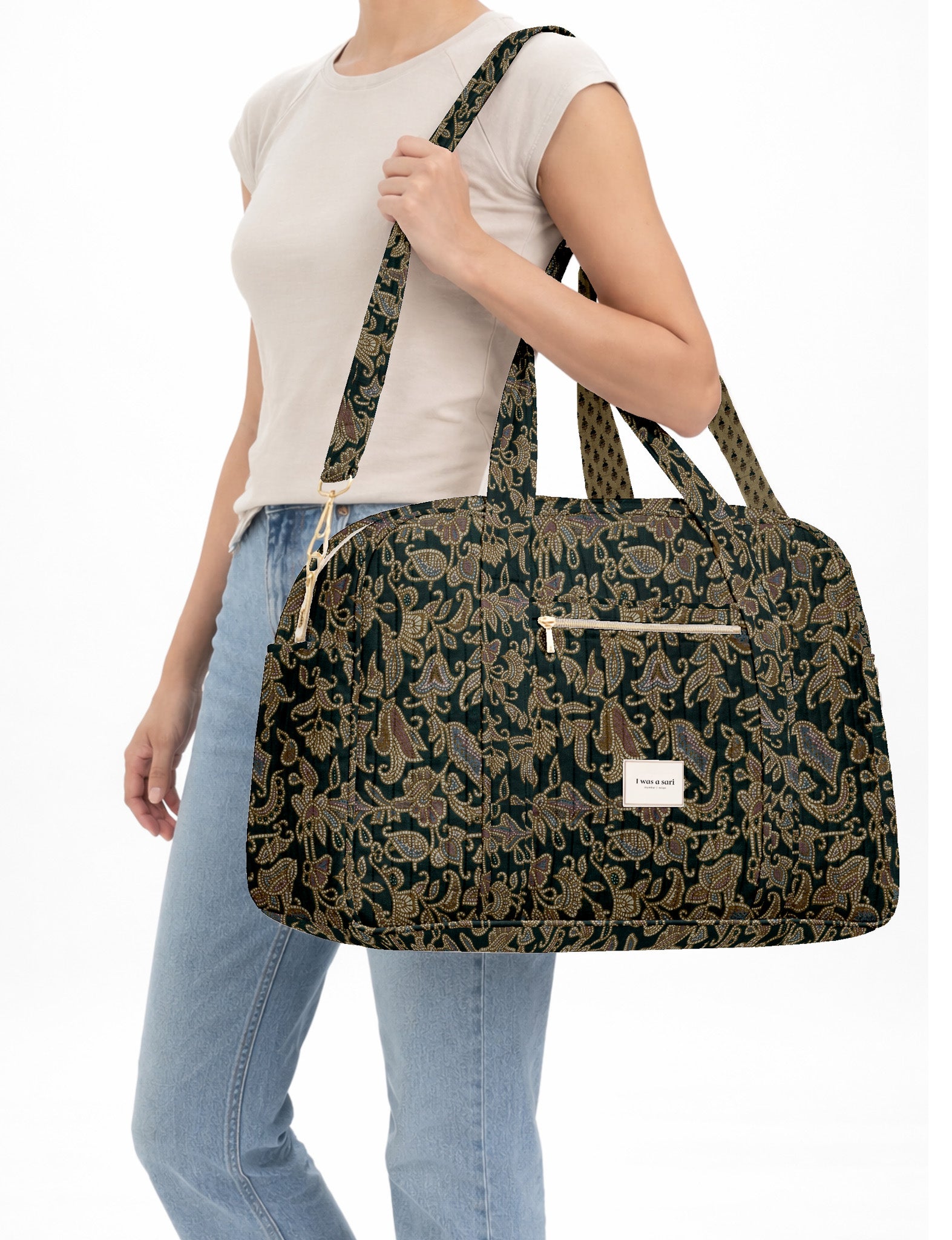 Brown quilted duffle bag with paisley pattern, front zip pocket, dual handles, and label reading "I was a sari"