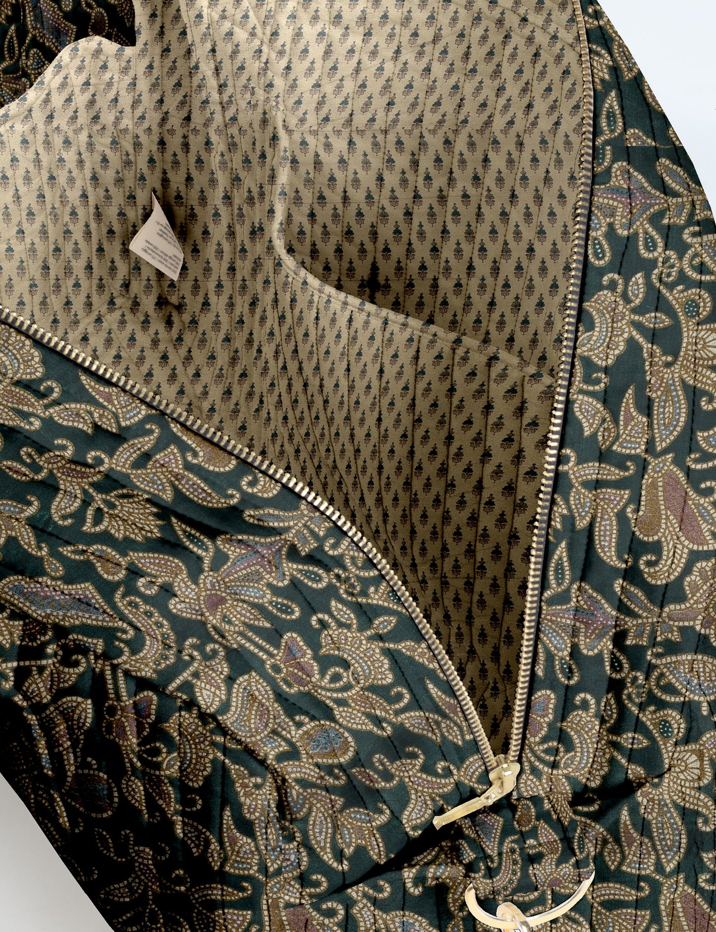 Brown quilted duffle bag with paisley pattern, front zip pocket, dual handles, and label reading "I was a sari"