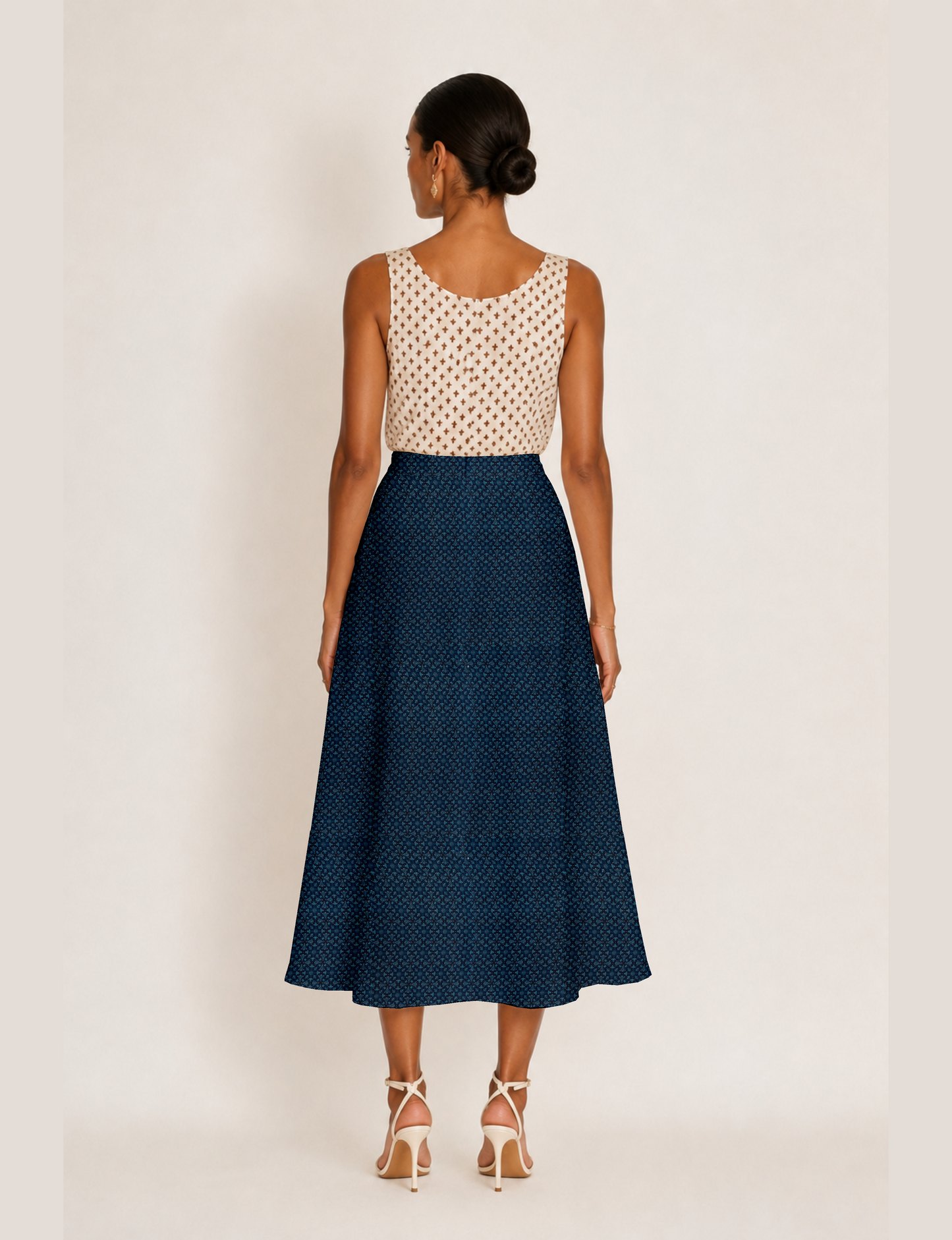 Woman wearing a yellow and black micro patterned A-line skirt with front slit, paired with beige sleeveless top and black