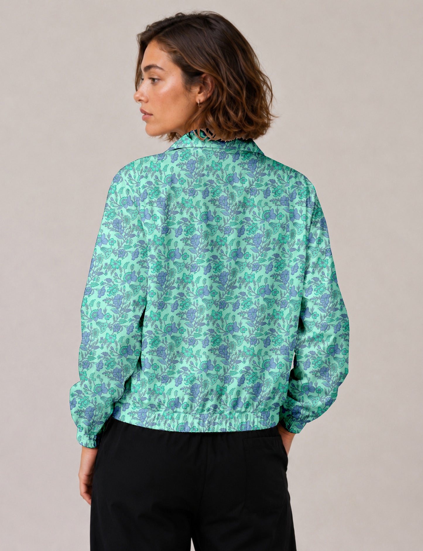 Brown floral bomber jacket with front zipper, elastic cuffs and hem, hanging on white hanger, red floral inner lining visible