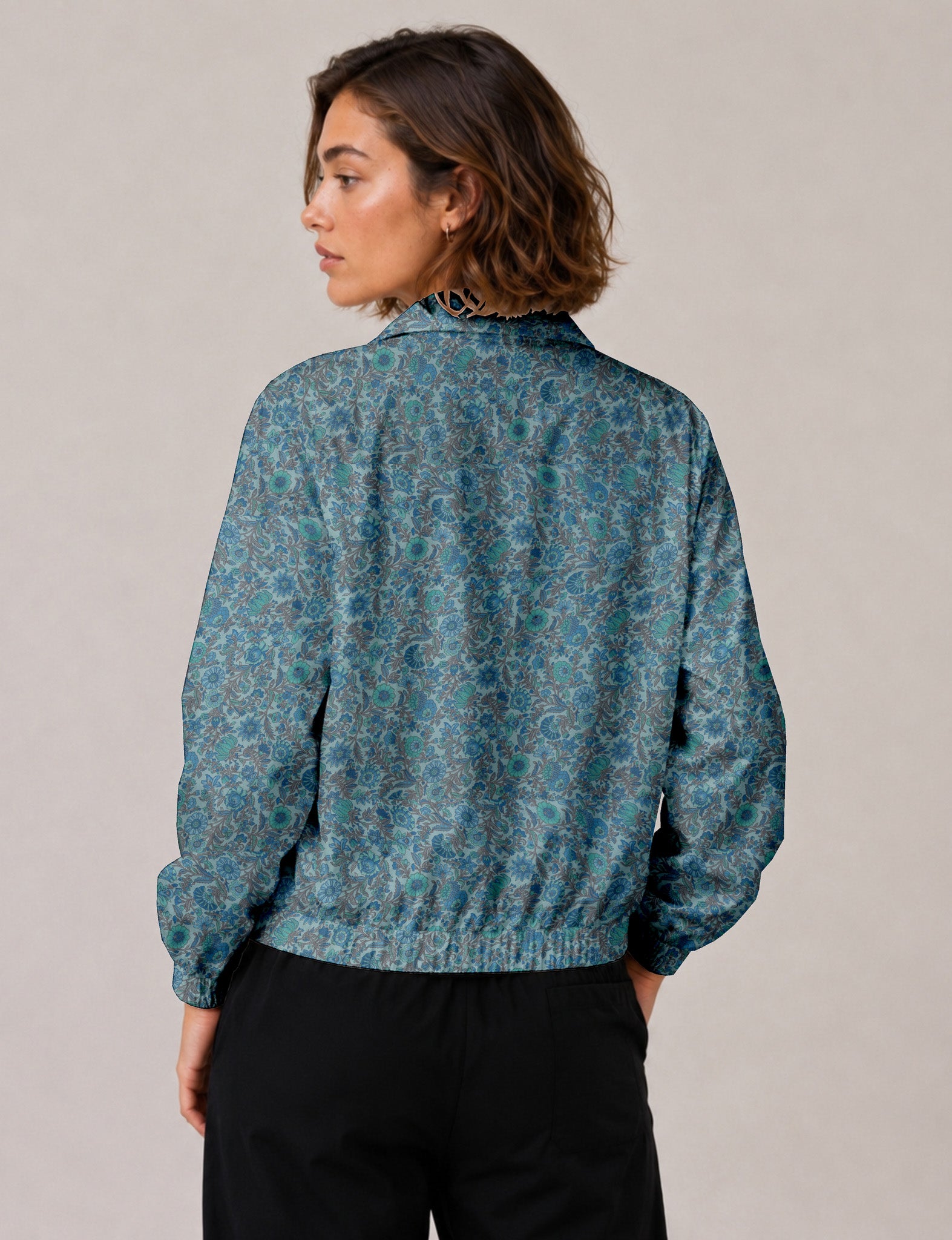 Brown floral bomber jacket with front zipper, elastic cuffs and hem, hanging on white hanger, red floral inner lining visible