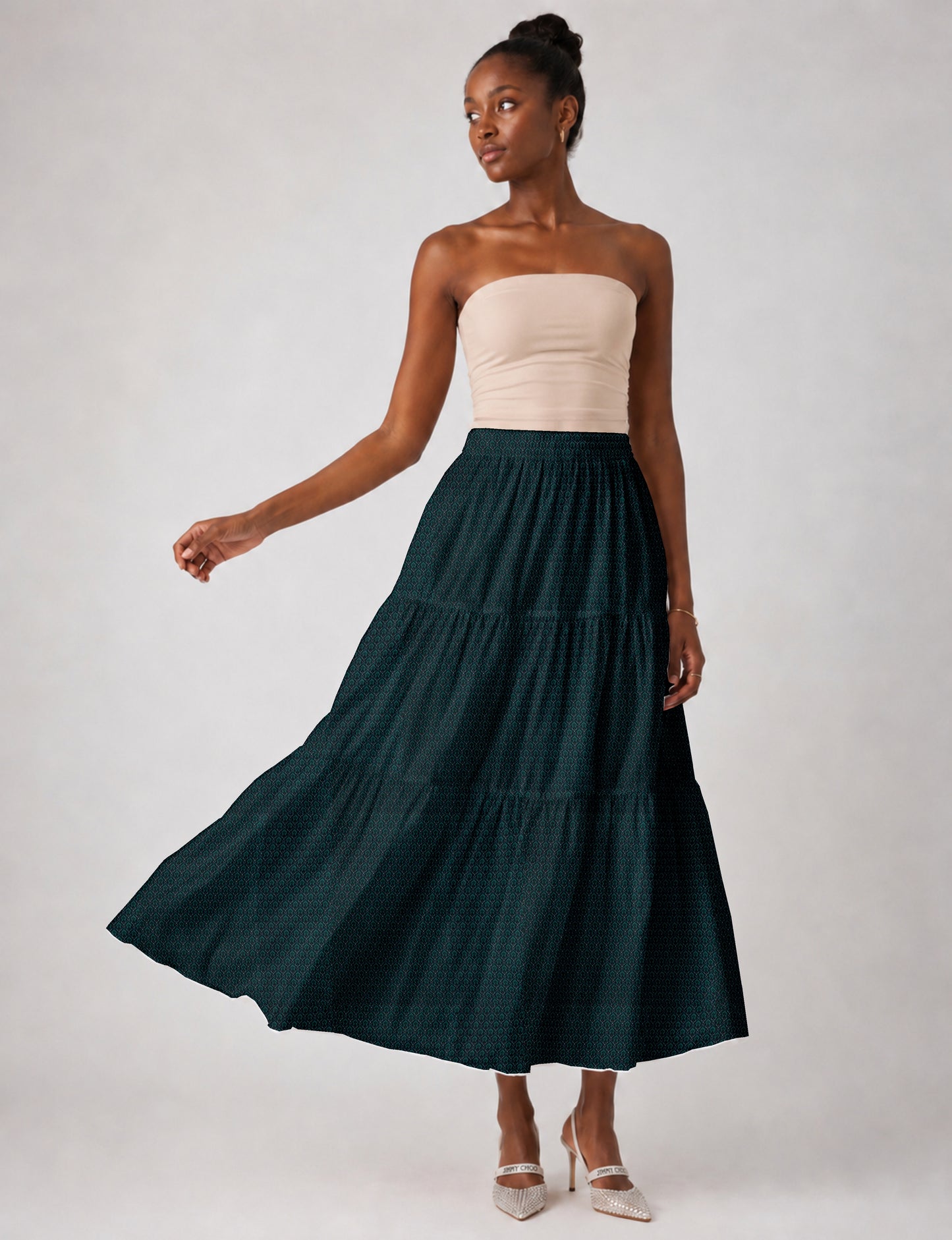 Woman wearing a yellow midi tiered skirt with a small geometric pattern, paired with a beige strapless top and white heels