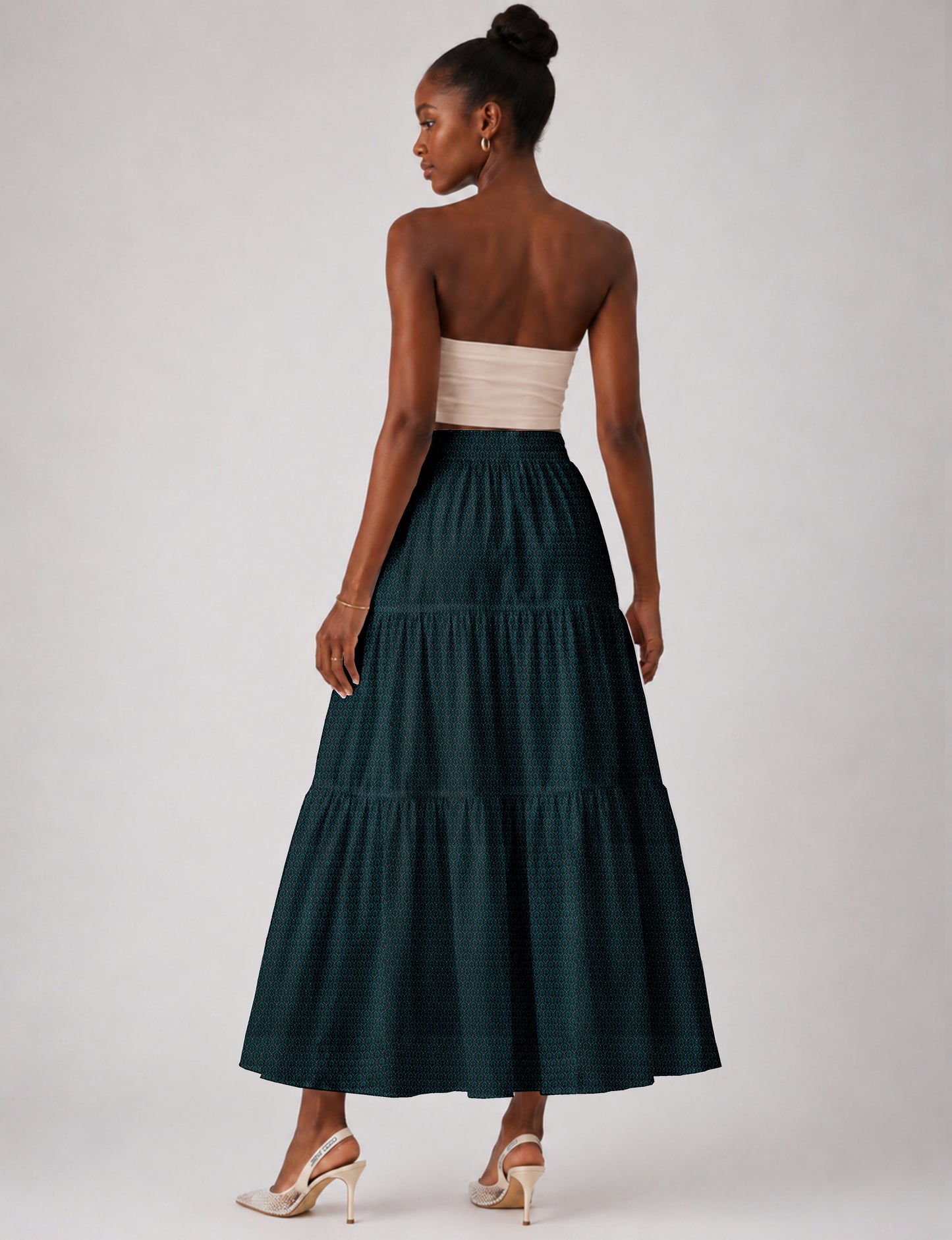Woman wearing a yellow midi tiered skirt with a small geometric pattern, shown from the back, paired with beige top and