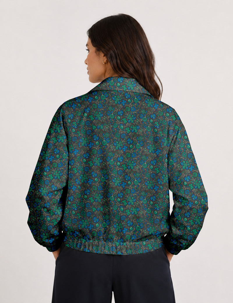 Woman wearing a yellow floral bomber jacket with front zipper, elastic cuffs, and side pockets, shown from front view