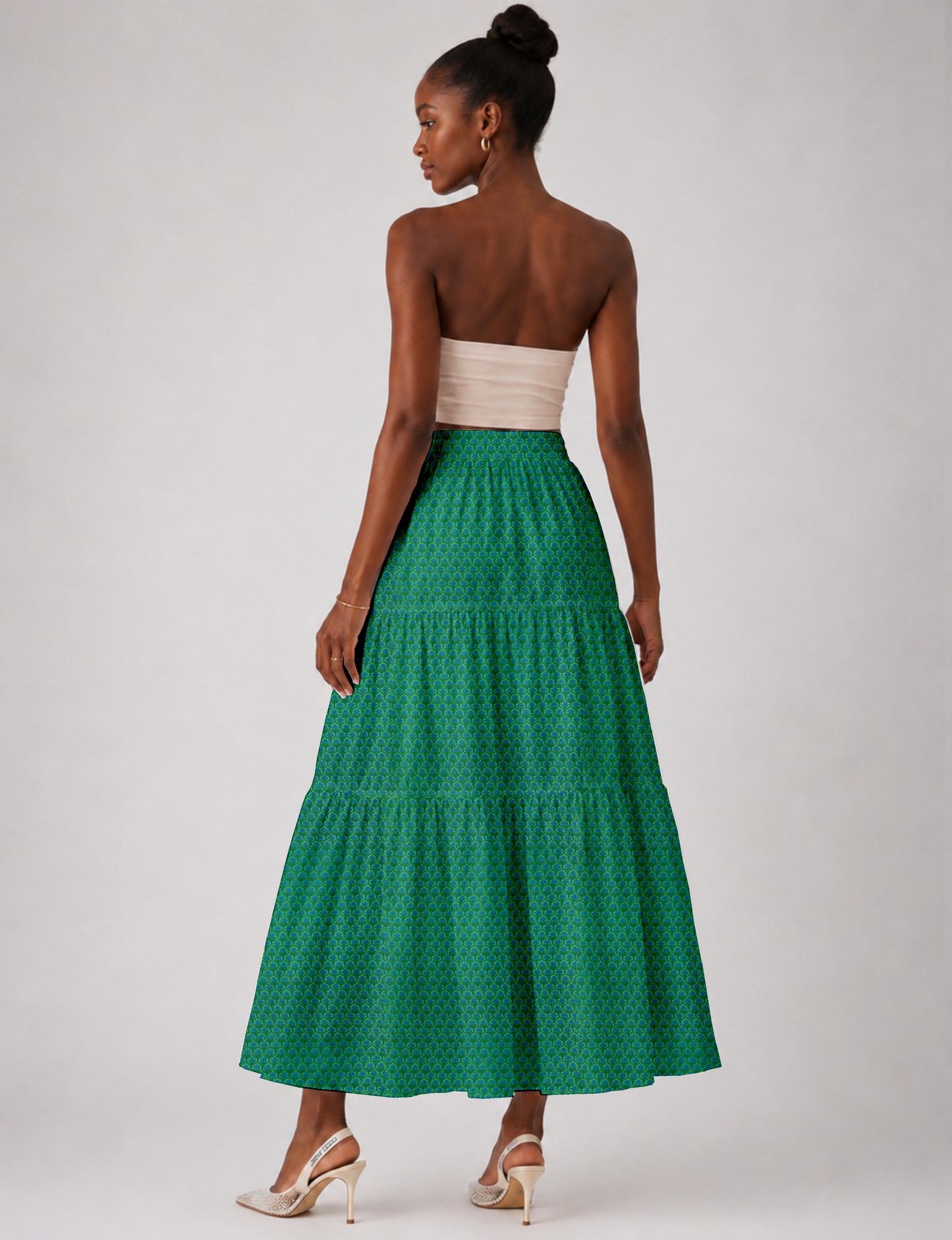 Woman wearing a yellow midi tiered skirt with a small geometric pattern, paired with a beige strapless top and white heels