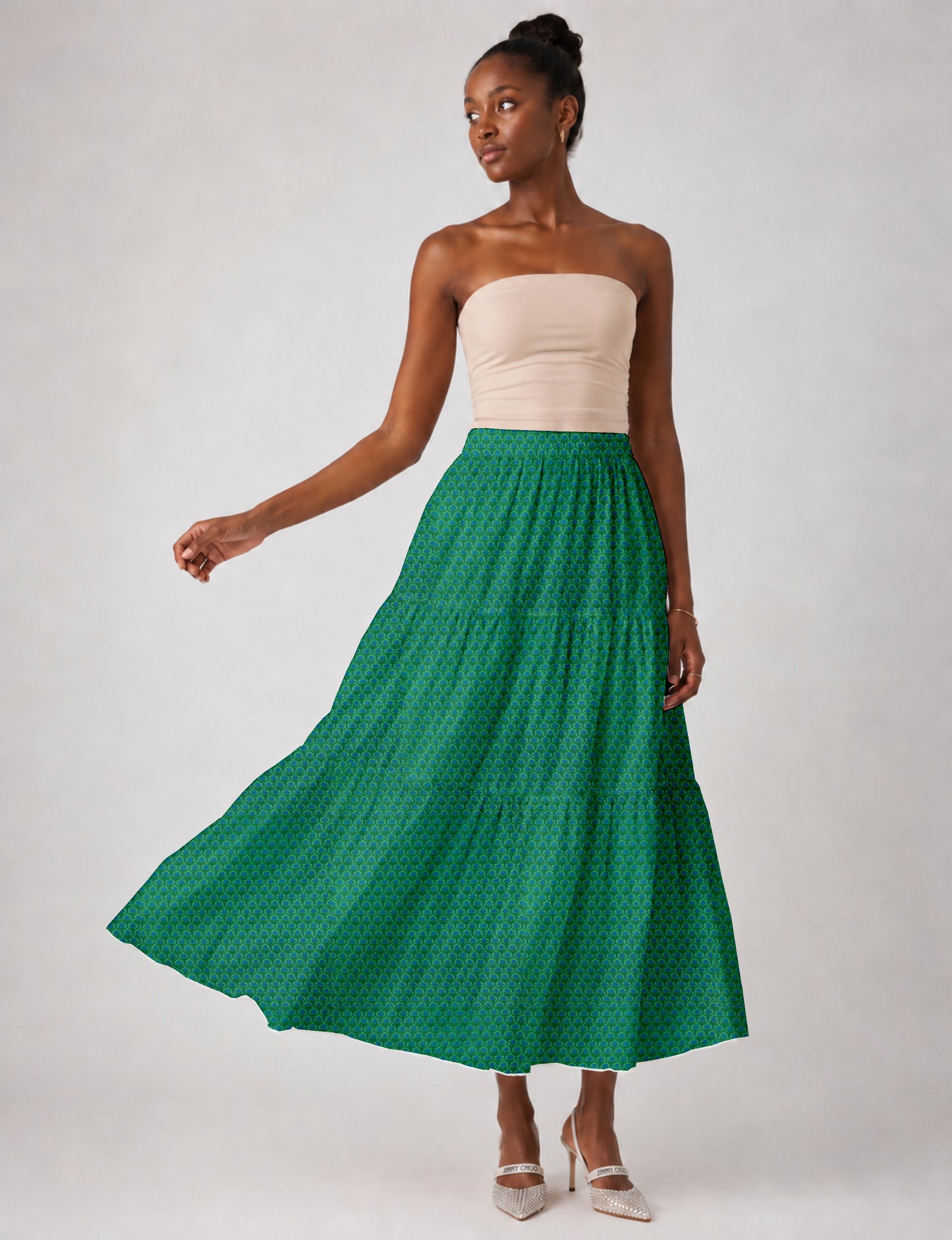 Woman wearing a yellow midi tiered skirt with a small geometric pattern, shown from the back, paired with beige top and