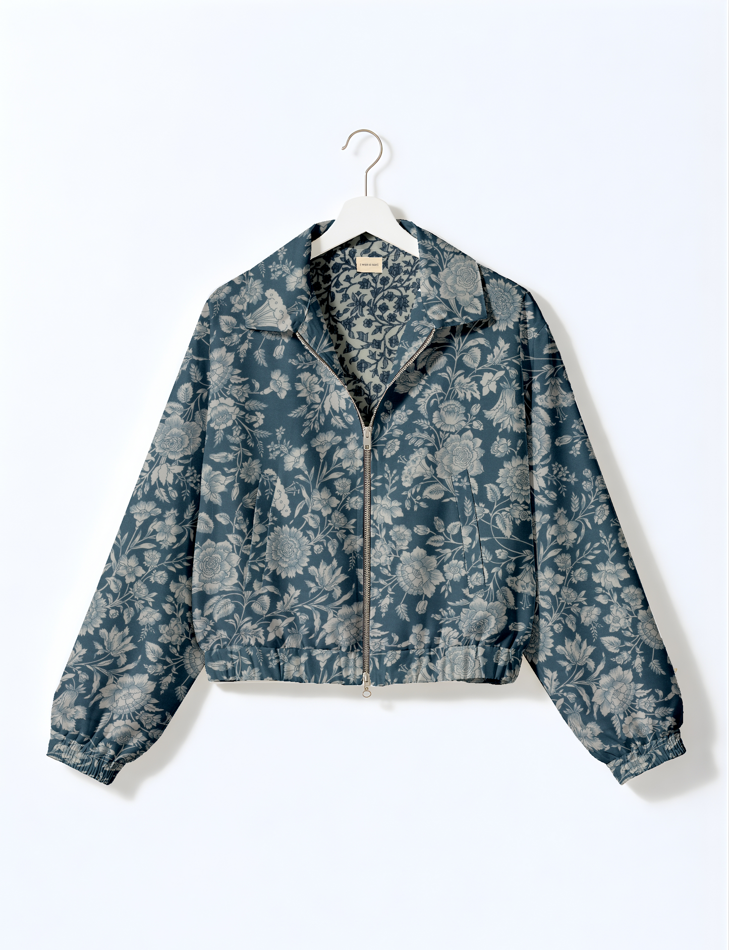 Women's cropped bomber jacket with twin metallic front zippers, welt pockets, elasticated hem and cuffs, and contrast sari print lining.
