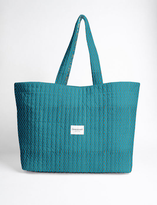 Quilted yellow tropical patterned beach bag with long handles and white label reading "I was a sari" front view