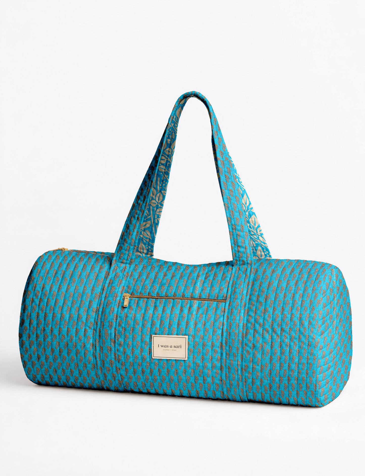 Brown paisley quilted bowling bag with front zipper pocket, held by person wearing white shirt and light blue jeans