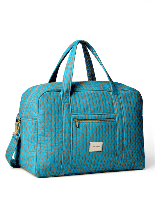 Brown quilted duffle bag with paisley pattern, front zip pocket, dual handles, and label reading "I was a sari"