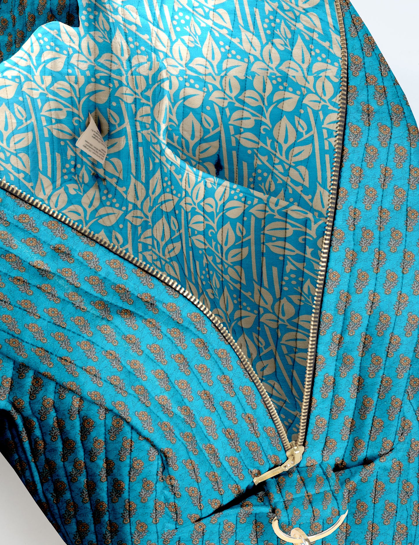 Brown quilted duffle bag with paisley pattern, front zip pocket, dual handles, and label reading "I was a sari"