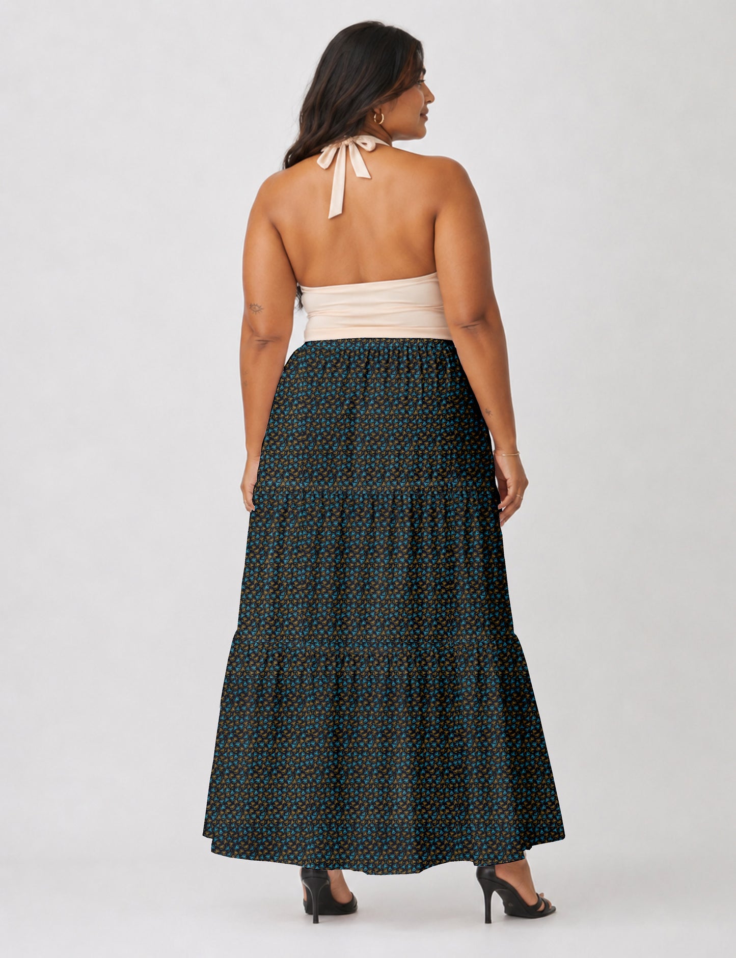 Woman wearing a yellow midi tiered skirt with a small geometric pattern, shown from the back, paired with beige top and