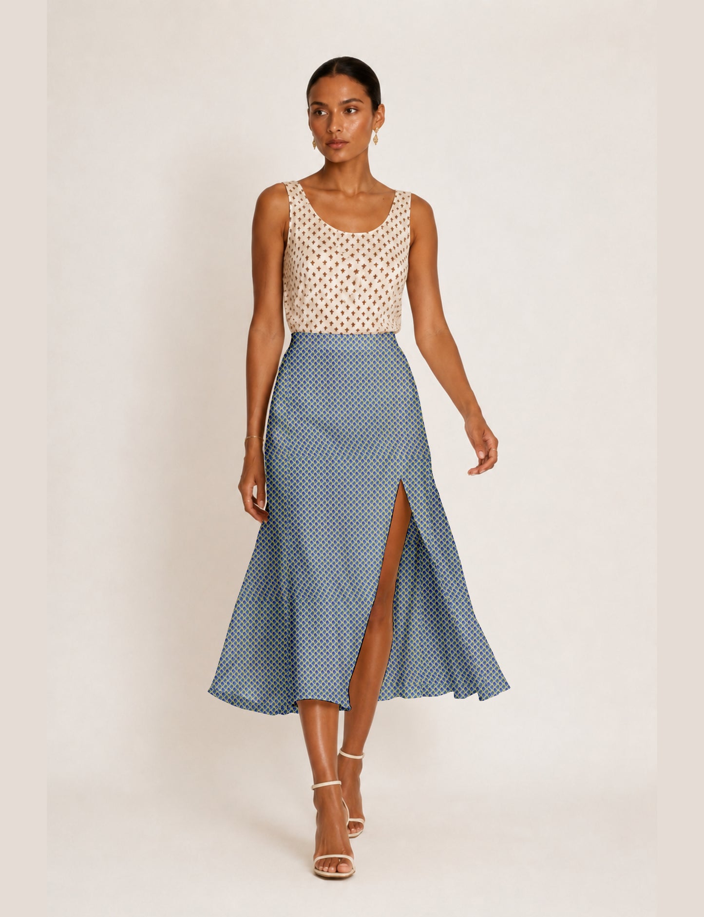 Woman wearing a yellow and black micro patterned A-line skirt with front slit, paired with beige sleeveless top and black