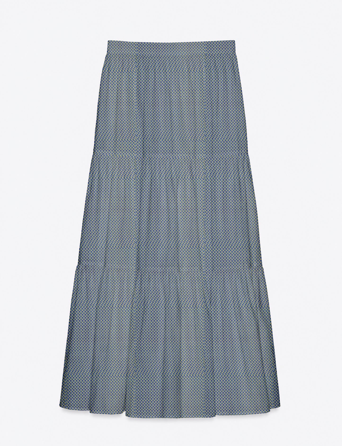 Woman wearing a yellow midi tiered skirt with a small geometric pattern, paired with a beige strapless top and white heels