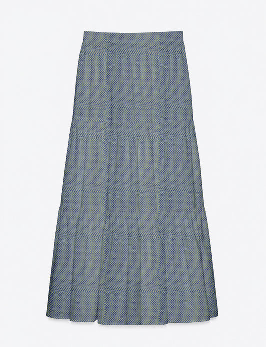Woman wearing a yellow midi tiered skirt with a small geometric pattern, paired with a beige strapless top and white heels