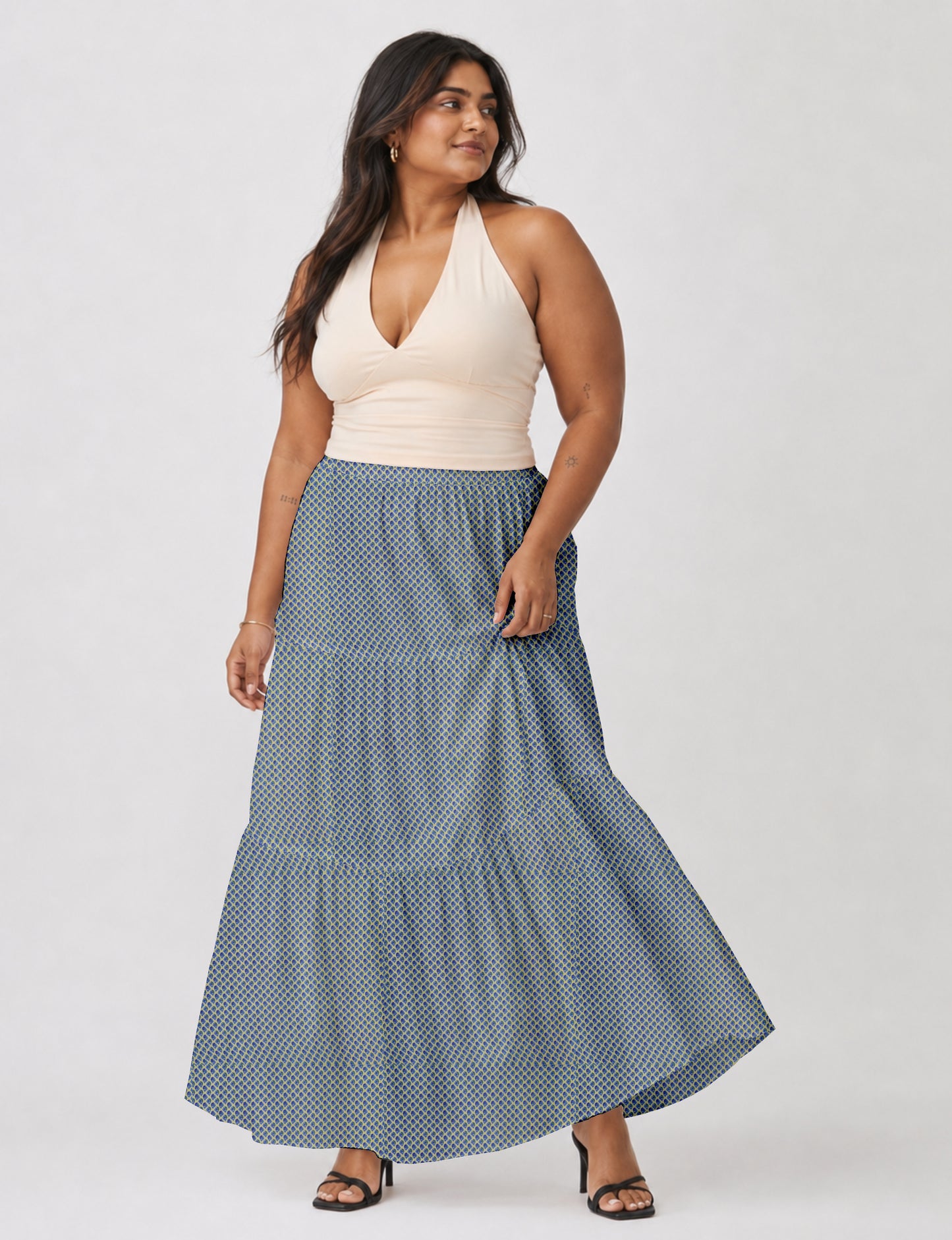 Woman wearing a yellow midi tiered skirt with a small geometric pattern, shown from the back, paired with beige top and